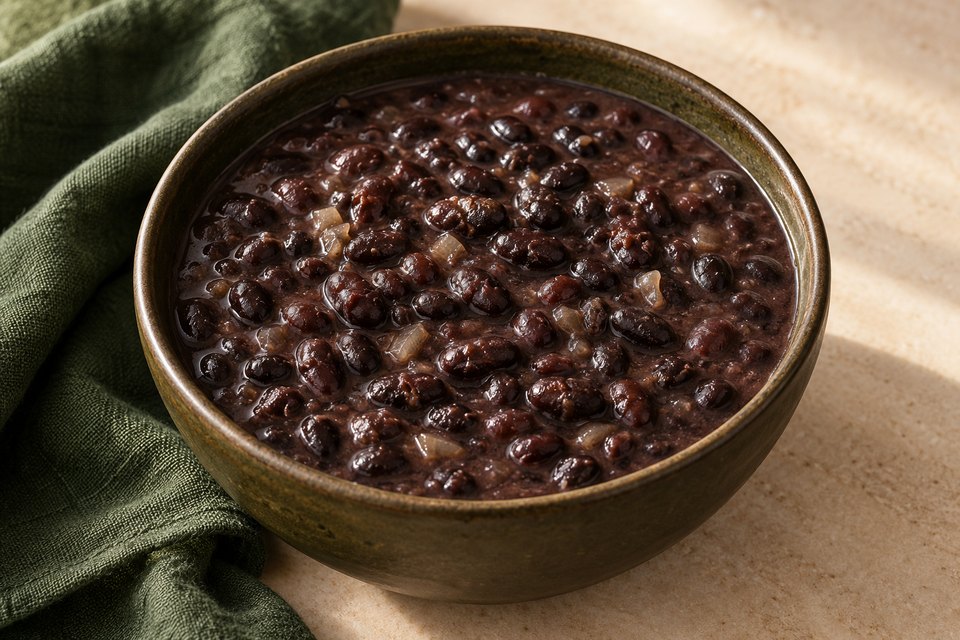 Black beans in dark broth with softened onion, in a ceramic bowl; AI illustration.